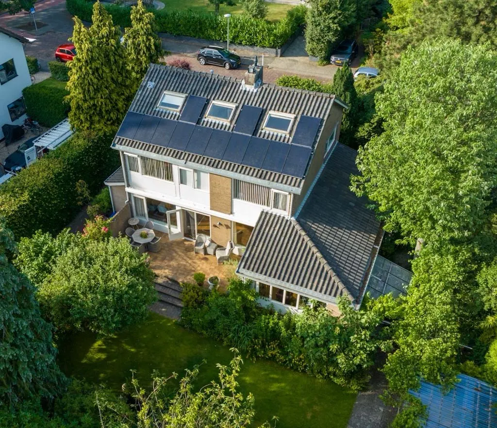 Luchtfoto van woning, dak met zonnepanelen en perceel